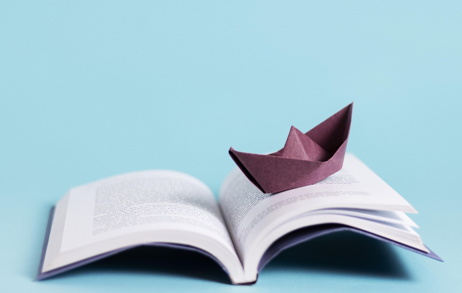 Photo d'un livre avec un bateau en papier qui semble voguer sur le livre