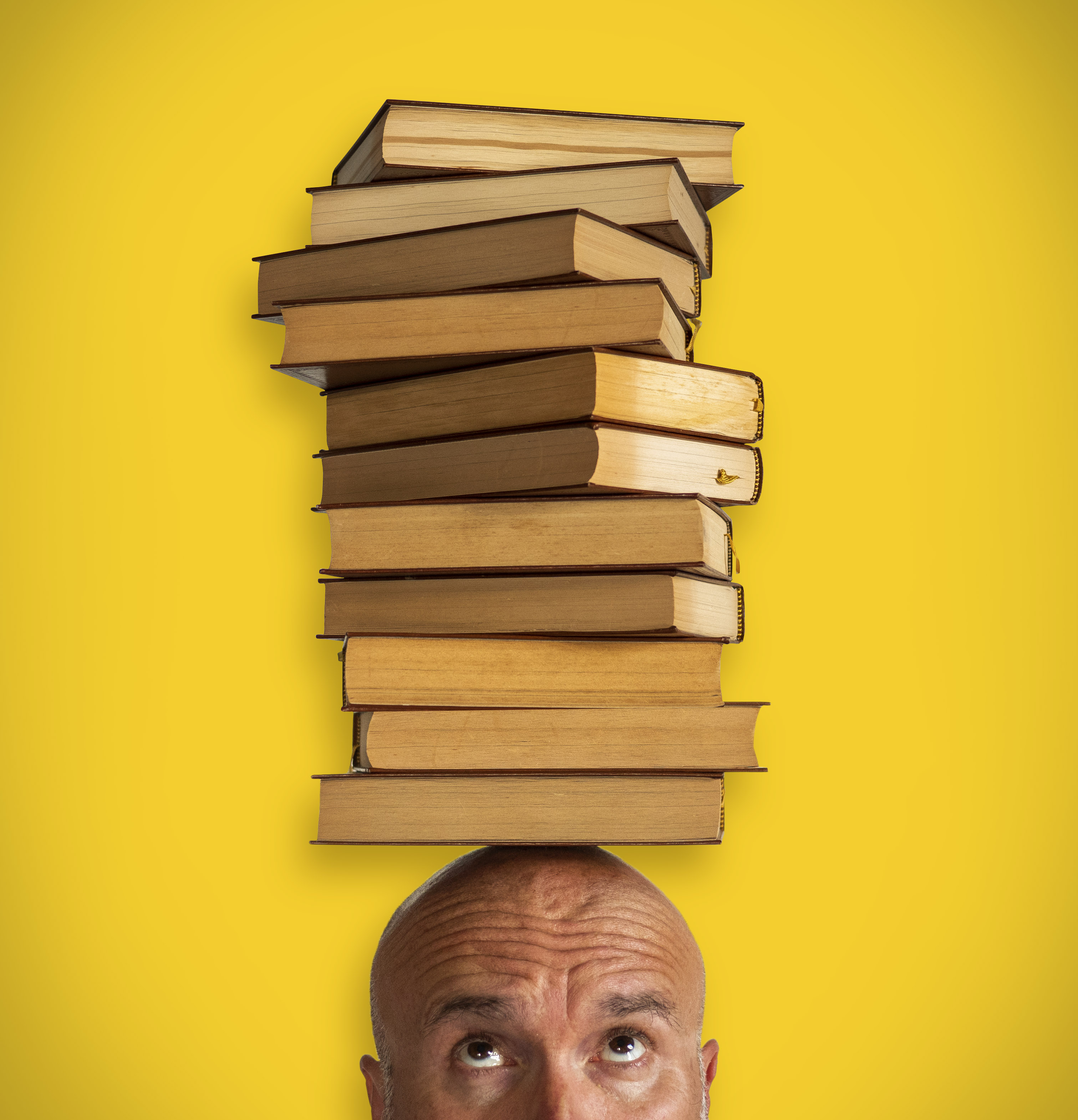 portrait artiste colonne de livres sur la tête