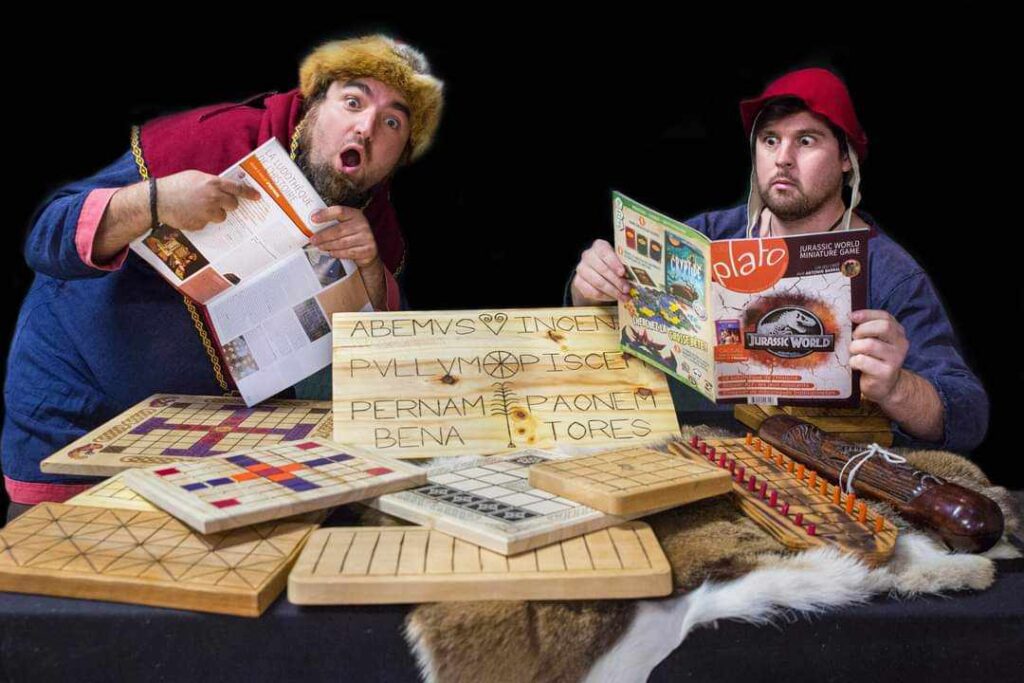 personnes habillées à l'époque du moyen-âge devant une table de jeux